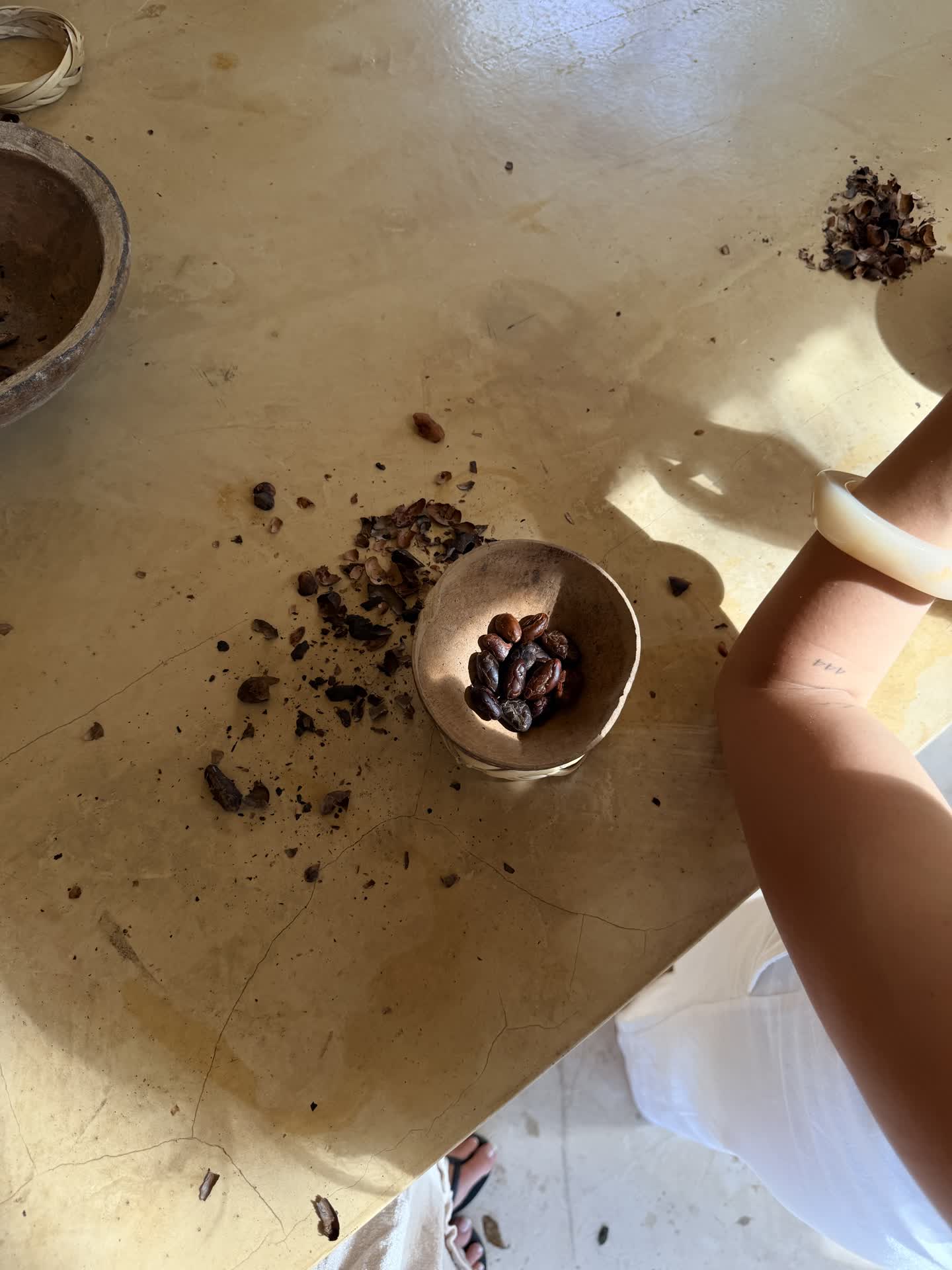 Cacao beans in a carved wooden bowl on a sunlit table